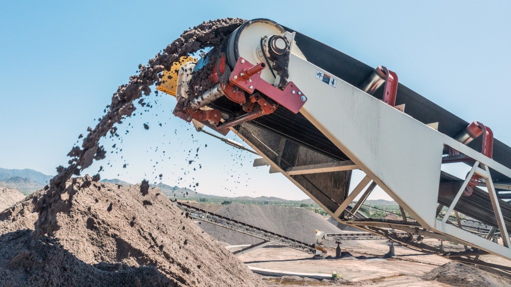 A conveyor belt cleaner operates at the top of a conveyor