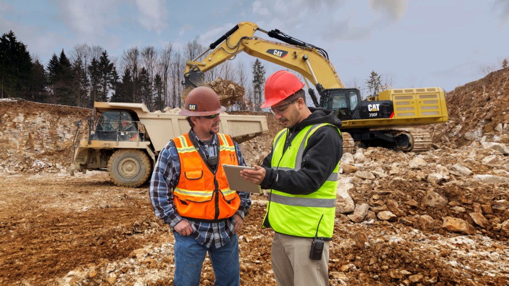 Two workers look at a tablet on a job site