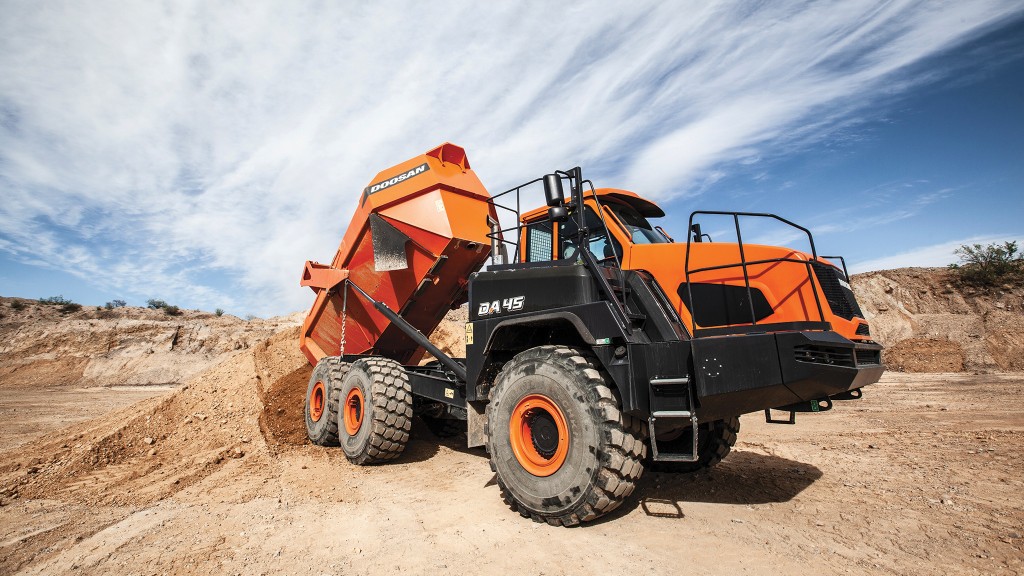 An articulated dump truck dumps dirt on a job site