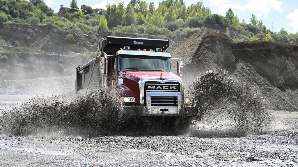 A Mack Granite drives through a mud puddle