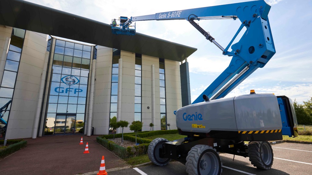 A telescoping boom lift reaching up to a building roof