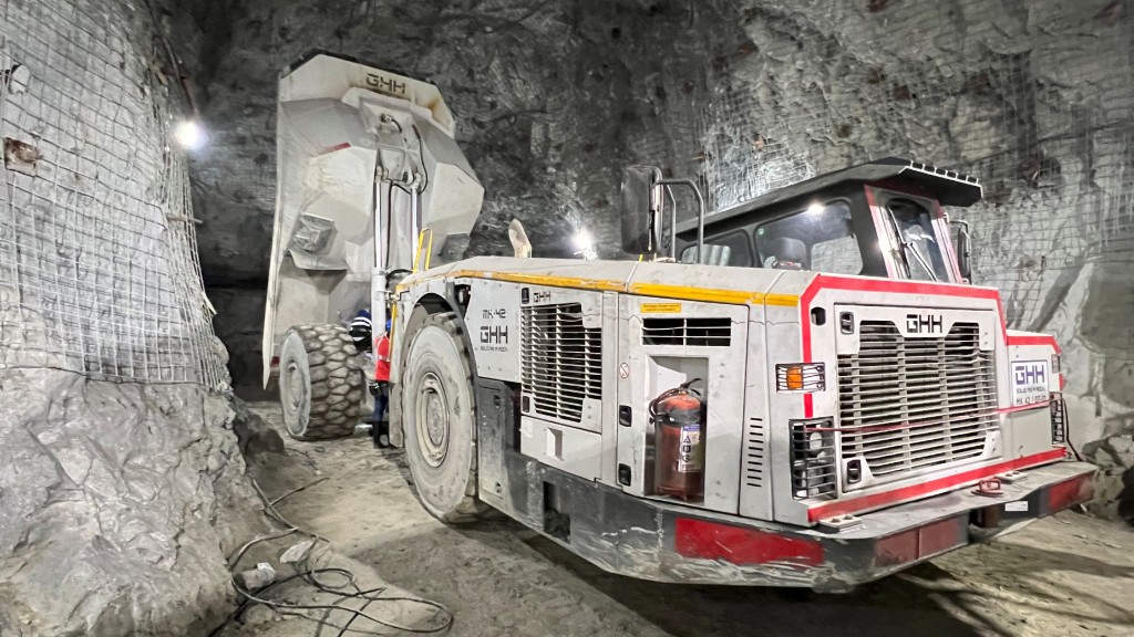 A dump truck has its bucket raised in an underground tunnel