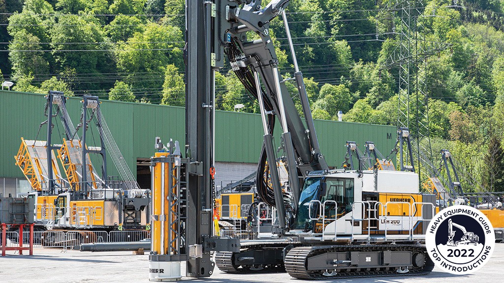 An electric drill rig is parked in the yard of a manufacturing facility