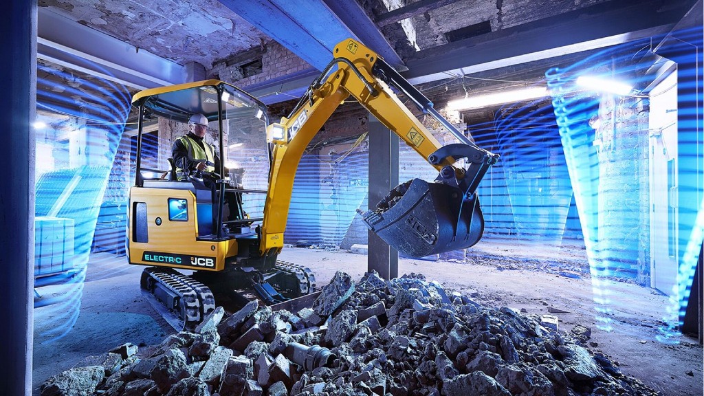 A mini excavator lifts rocks inside of a building