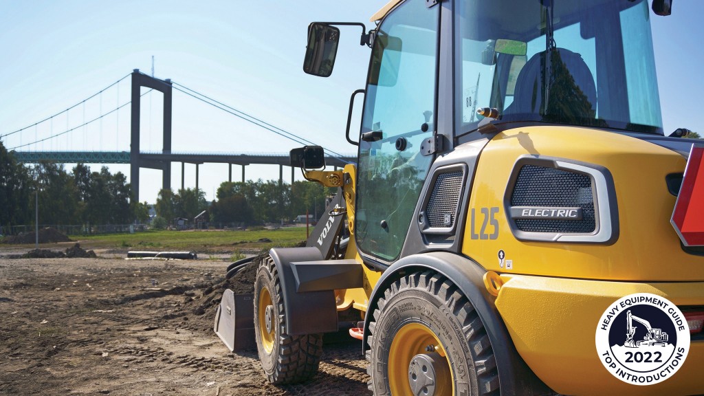 An electric wheel loader is parked with a bucket full of dirt on a job site