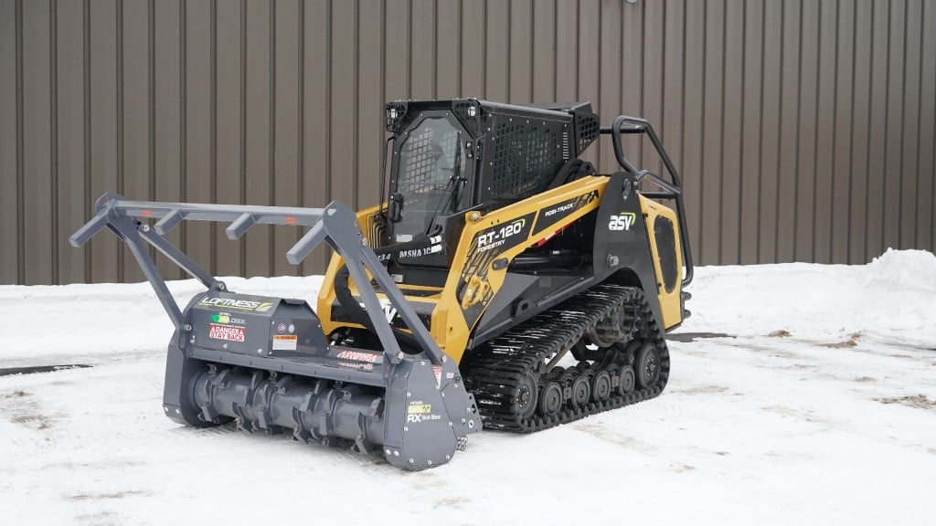 A compact track loader is parked in a parking lot filled with snow