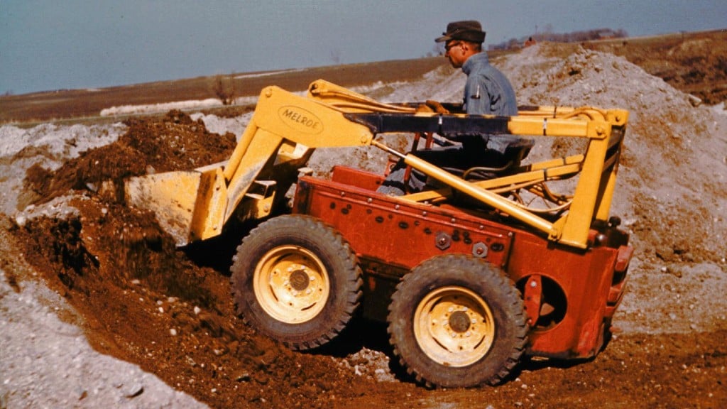 An operator uses a prototype skid-steer loader to lift a bucket of dirt