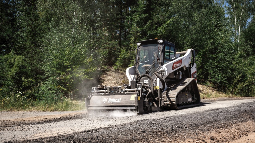 A compact track loader with a planer attachment working on a road