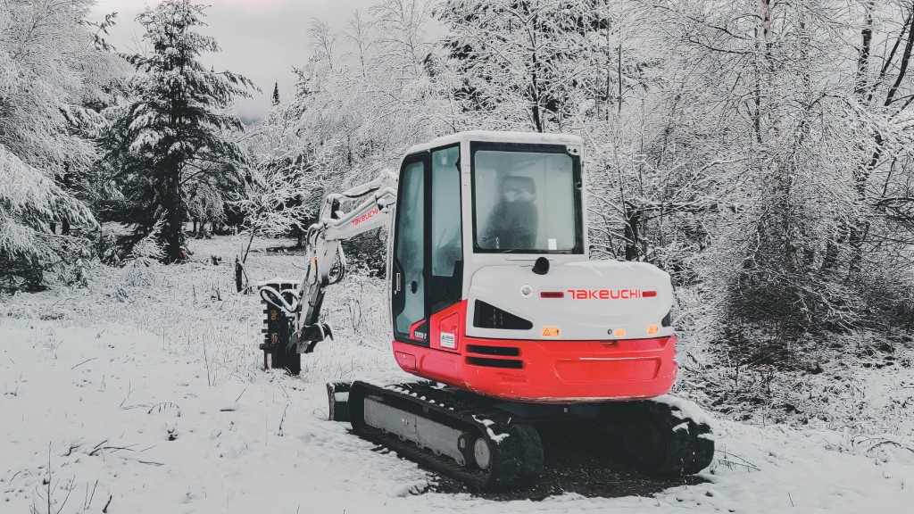 A compact excavator operates on a snowy job site