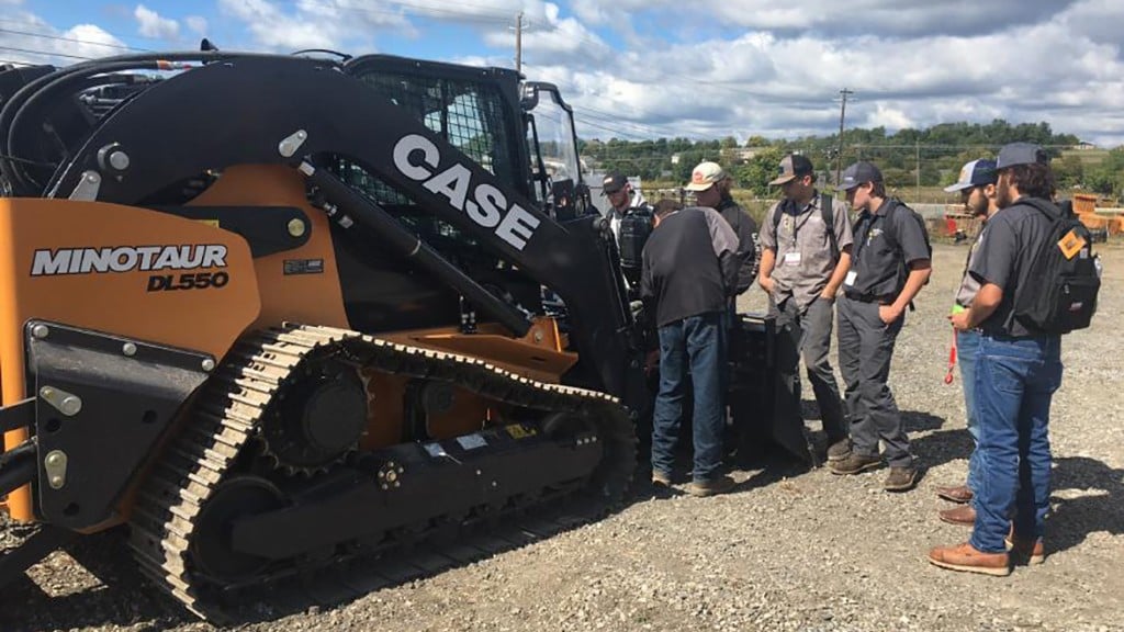 People tour a compact dozer loader in a parking lot
