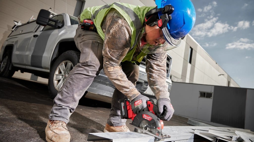 A worker uses a saw to cut a piece of metal