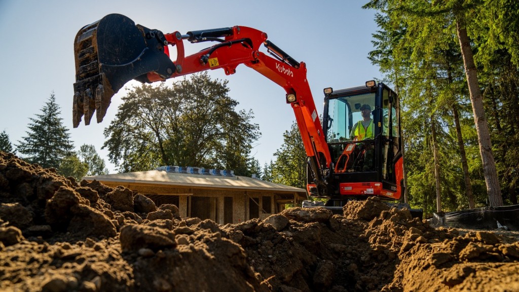 A compact excavator working above a trench.