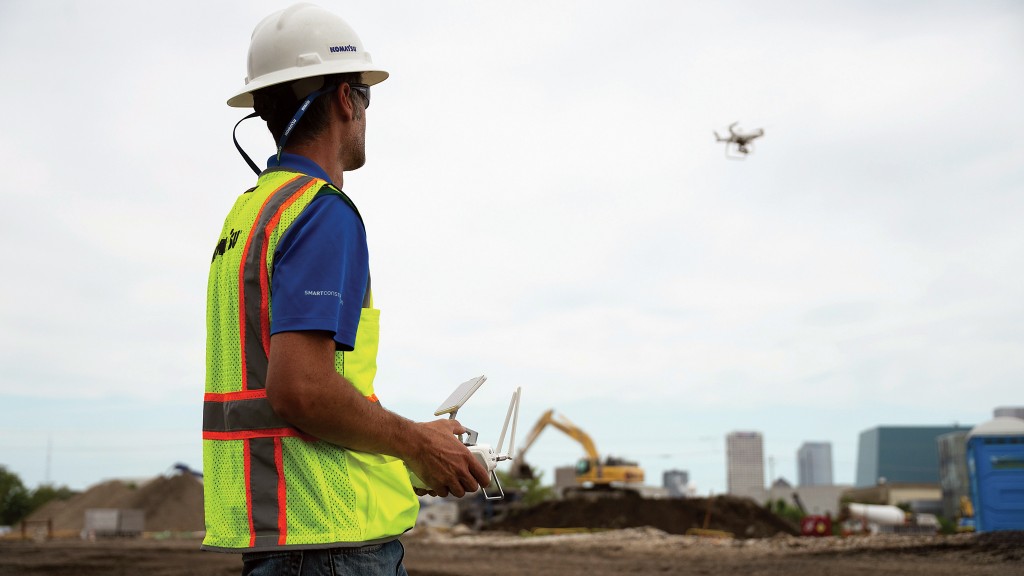A worker operators a drone on a job site