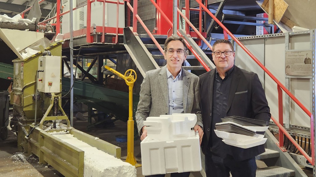 Two people hold polystyrene in a factory