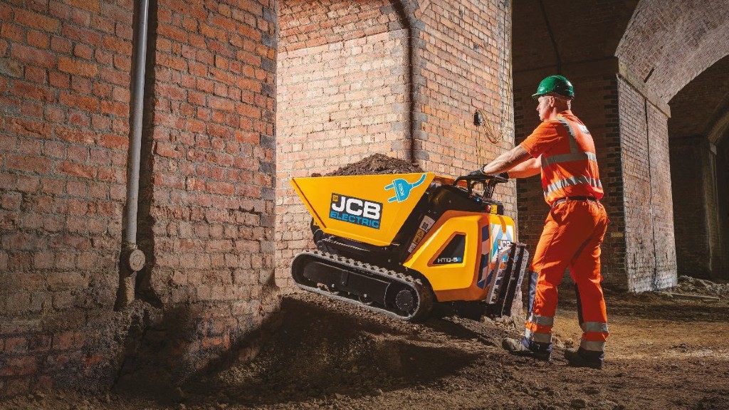 An operator drives an electric dumpster on a job site