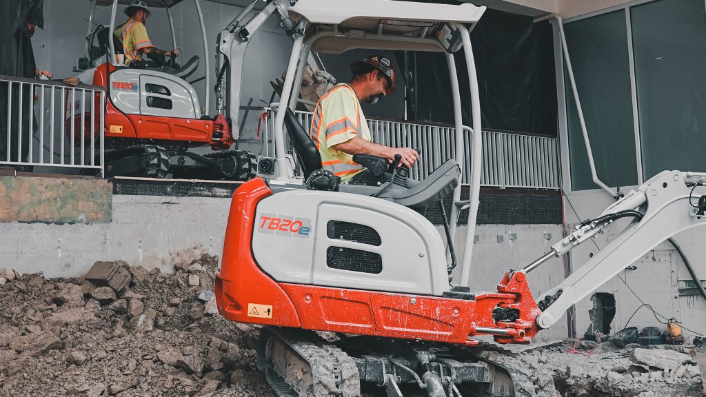 Two mini excavators working next to a building.