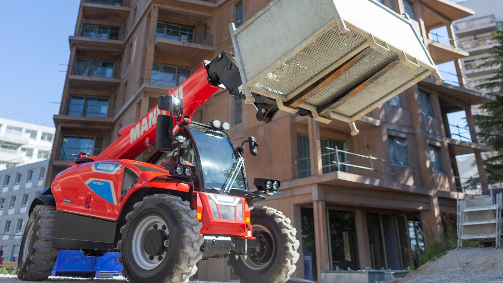 A battery-electric telescopic handler in front of a building