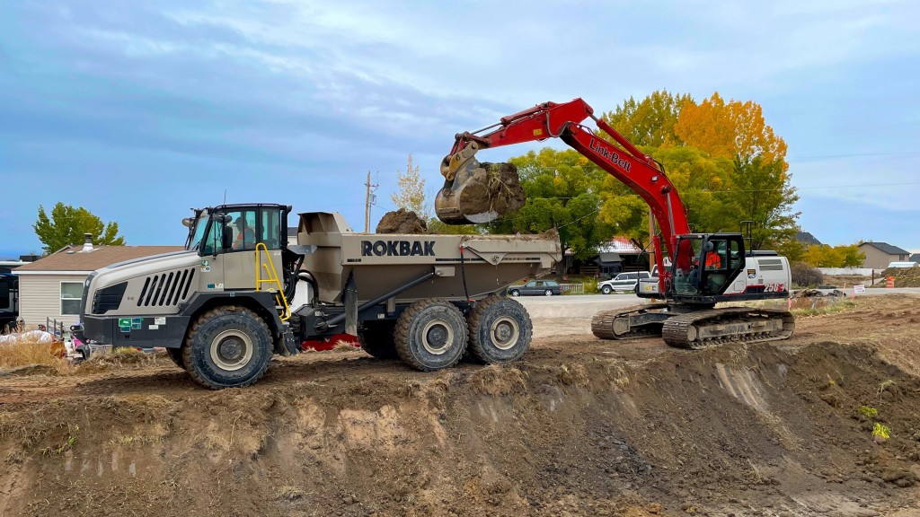 An excavator fills an articulated hauler up with dirt