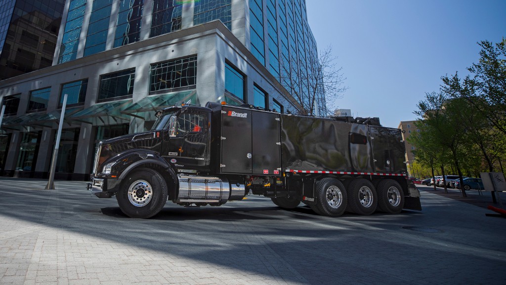 A hydrovac is parked near a large building