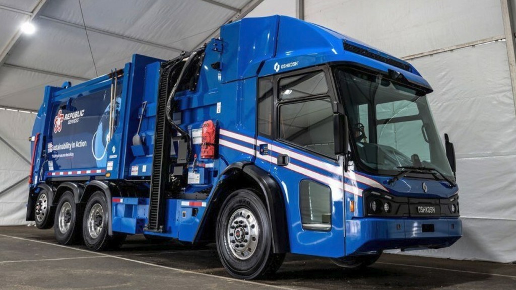 An electric collection truck is parked inside a tent