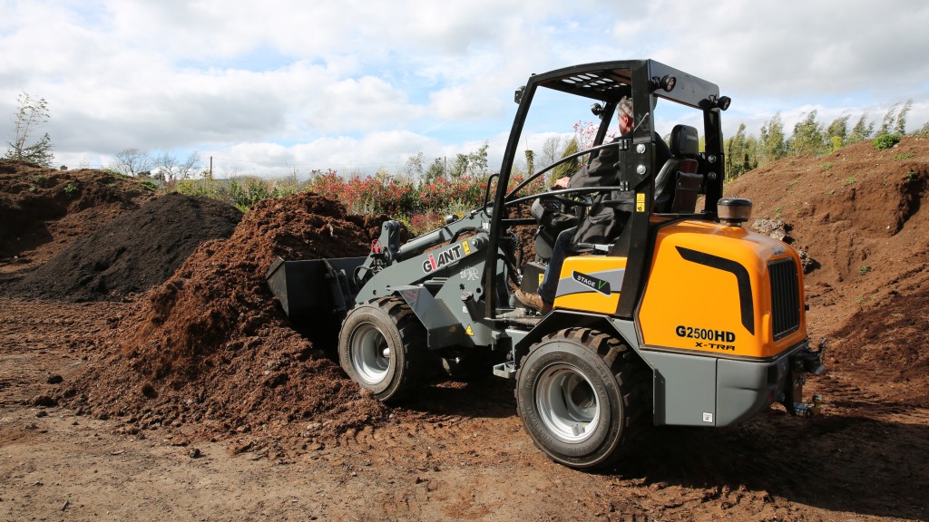 A compact wheel loader picks up a bucket of dirt on a job site