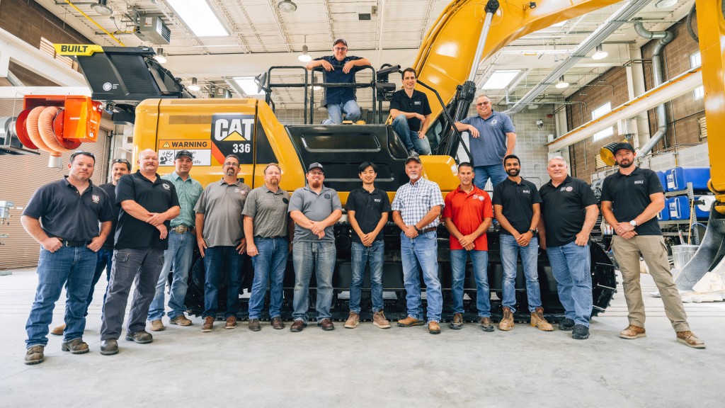 A group of people stand near an excavator equipped with autonomous technology