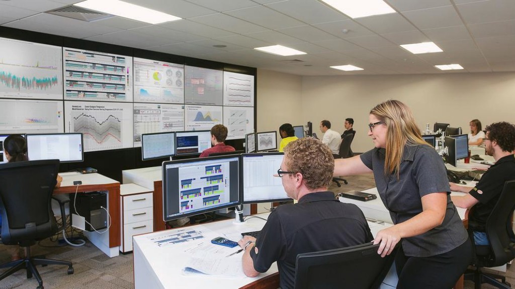 People work at computer stations in a large monitoring room