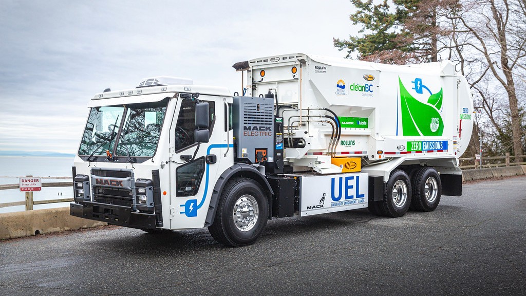 An electric collection truck is parked near the ocean