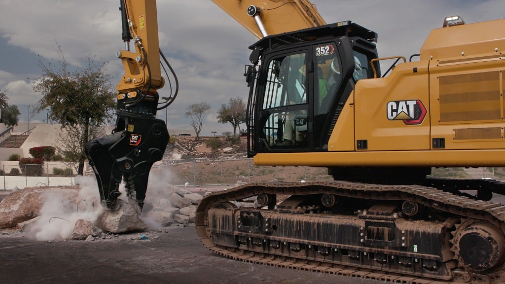 A straight boom excavator works to demolish a small structure