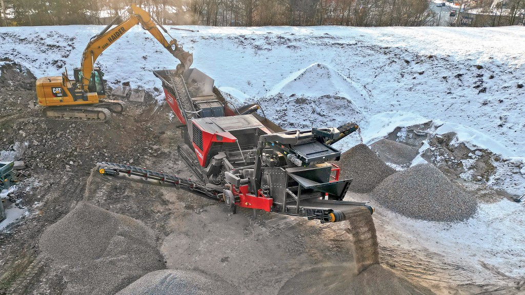 An excavator fills a crusher with large rocks