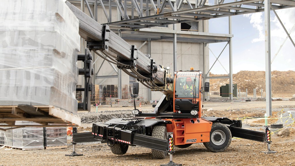 An operator lifts a pallet of building materials using a telehandler