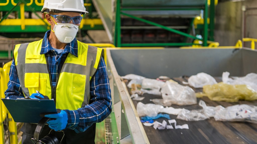 A worker in an MRF writes something down near a conveyor