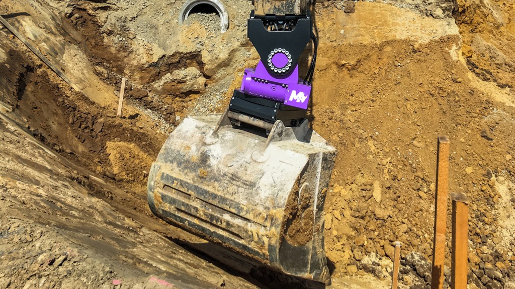 An excavator uses a tiltrotator to dig out a trench on a job site