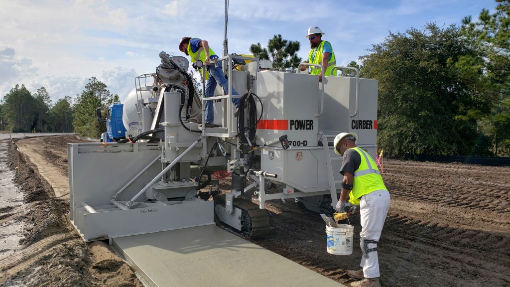 A slipform paver lays down a wet sidewalk