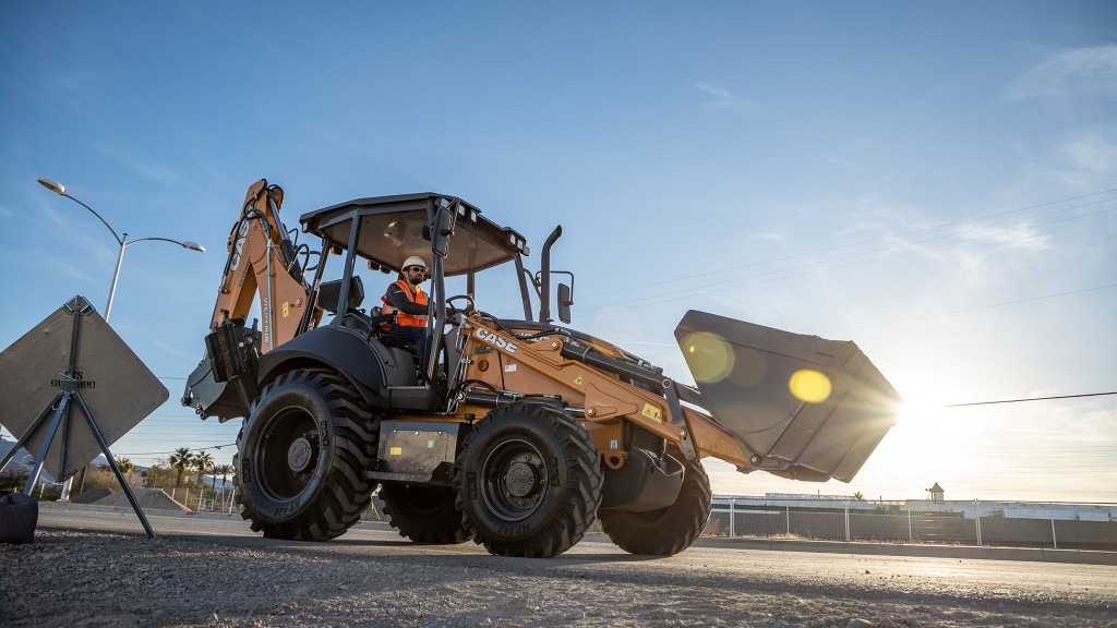 A backhoe loader against a sunrise