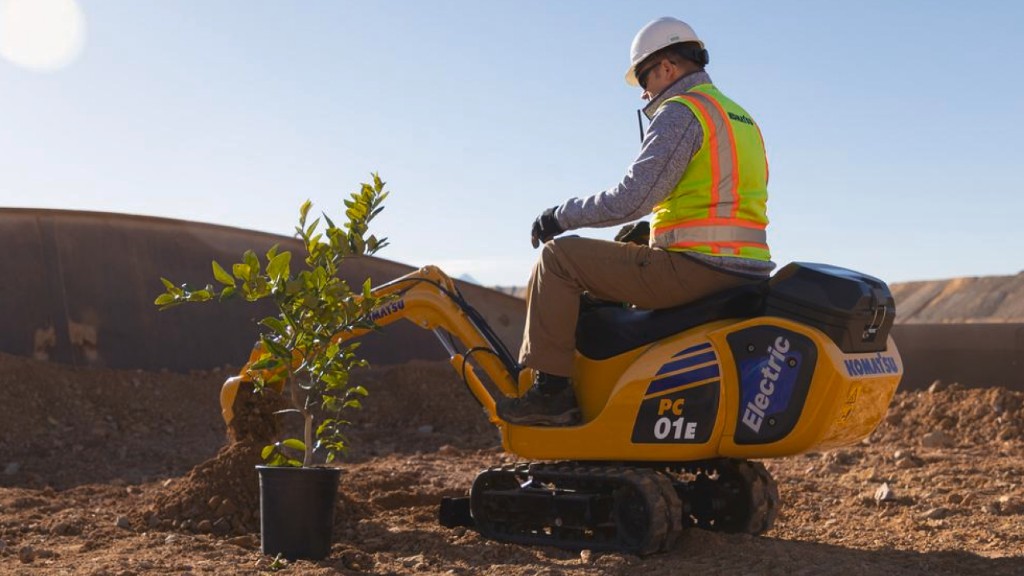 A mini electric excavator plants a tree