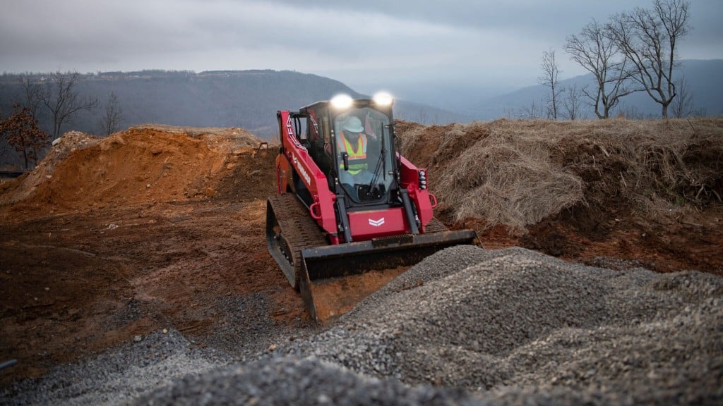 A compact track loader is about to dig into a pile