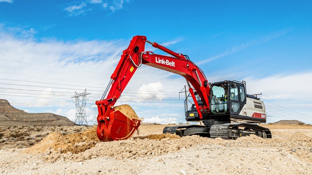 An excavator lifts a bucket full of dirt on a job site