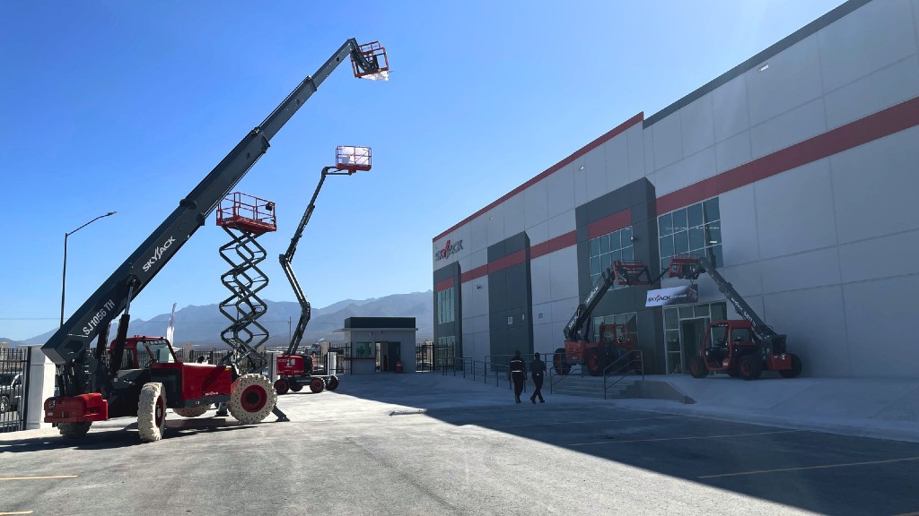 Several lifts are parked outside a manufacturing facility