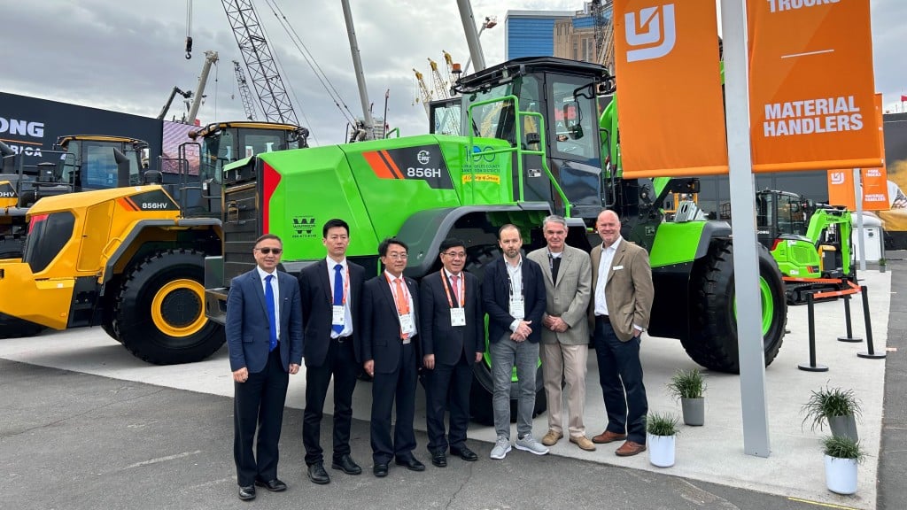 A group of people stand near a wheel loader