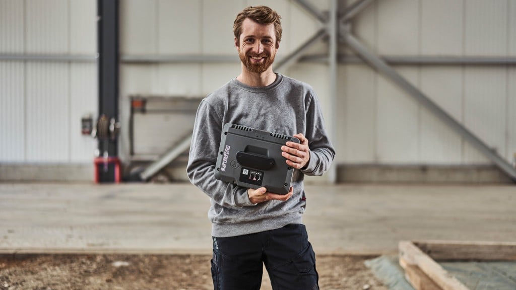 A man holds a battery in a warehouse