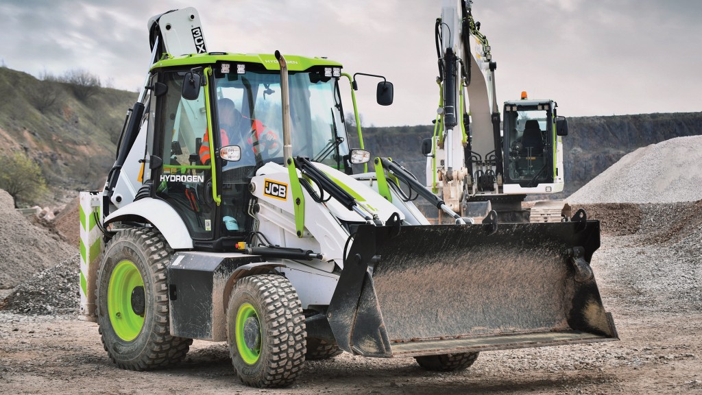 An operator drives a backhoe loader on a job site