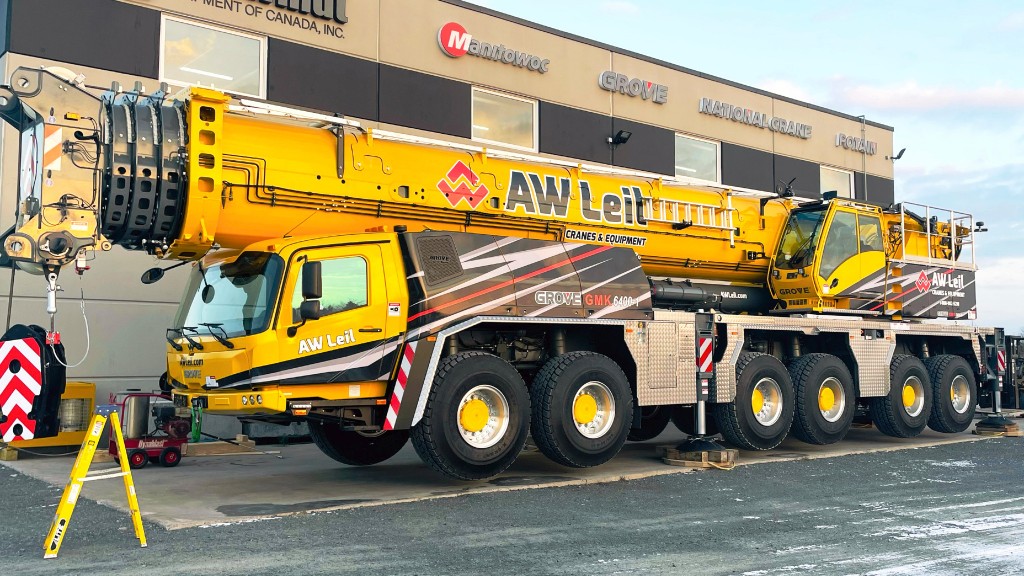 An all-terrain crane is parked near a Manitowoc building