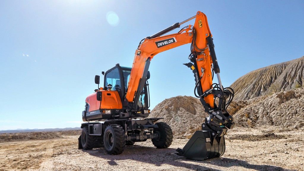 A wheeled mini excavator is parked on a empty job site