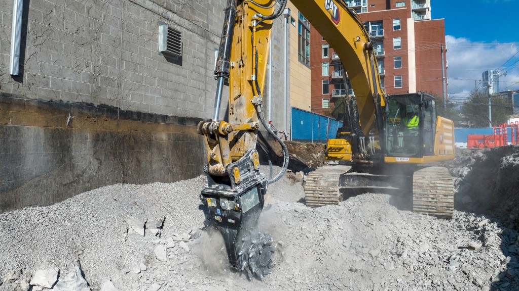 An excavator uses a rotary cutter to break up material on a job site