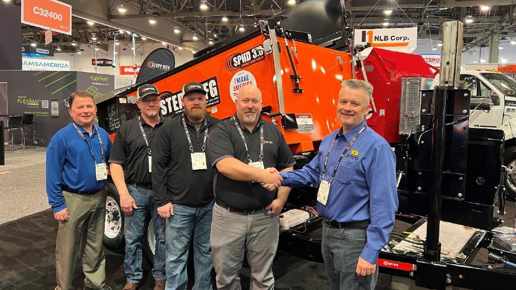 A group of people handshake on the floor of a trade show