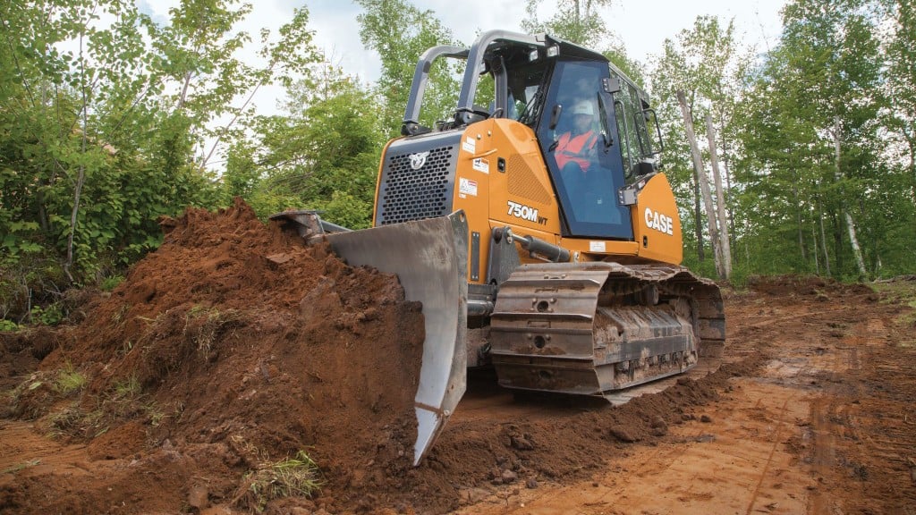 A dozer in a forested setting pushing dirt.