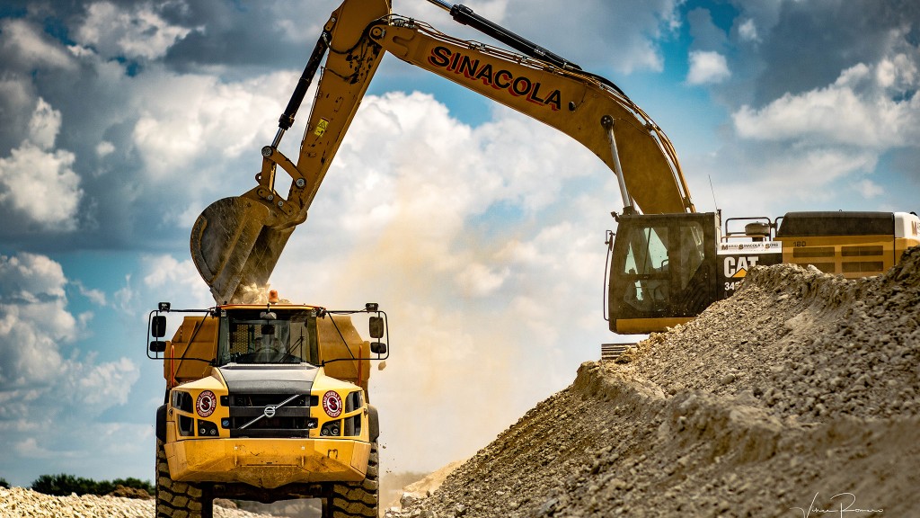 An excavator on a pile loads a dump truck