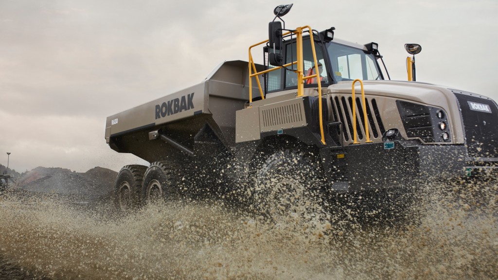 An articulated hauler drives through a muddy puddle