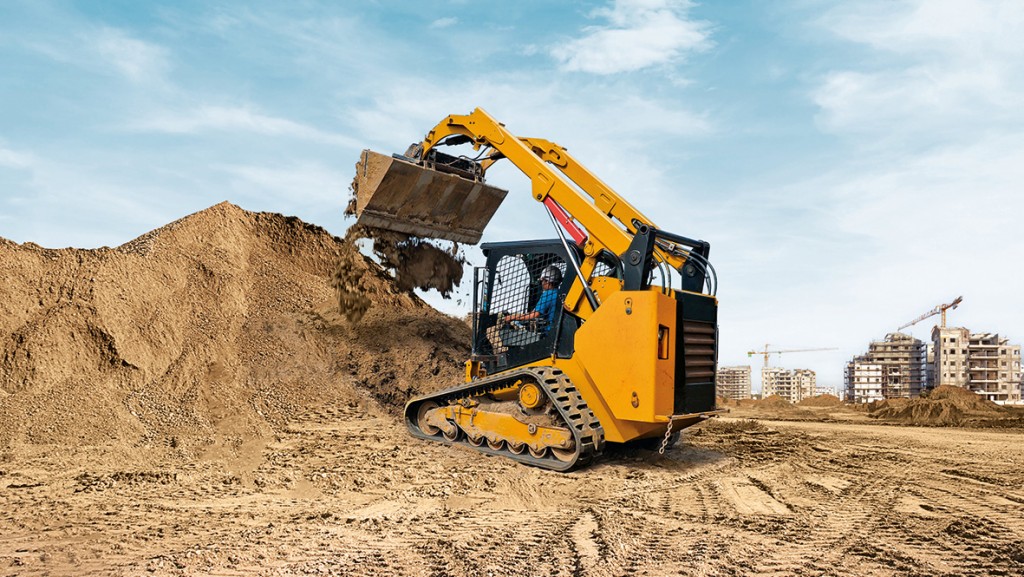 A compact track loader piling dirt on a job site.